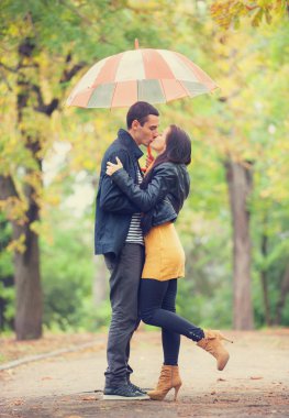 couplewith şemsiye Park'ta açık öpüşme