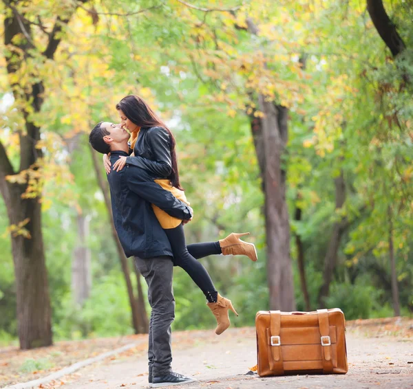 Paar mit Koffer küsst sich in Gasse im Park — Stockfoto