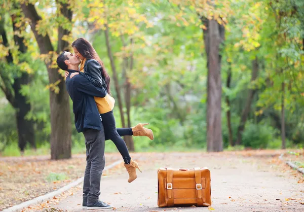 Paar mit Koffer küsst sich in Gasse im Park — Stockfoto