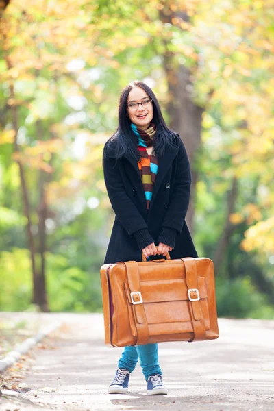 Esmer kız sonbahar sokak Park, bavul holding — Stok fotoğraf