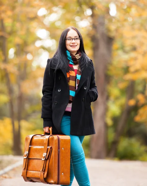 Brunette fille tenant valise à l'allée d'automne dans le parc — Photo