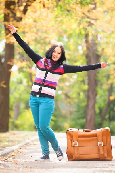 Esmer kız sonbahar sokak Park, bavul holding — Stok fotoğraf