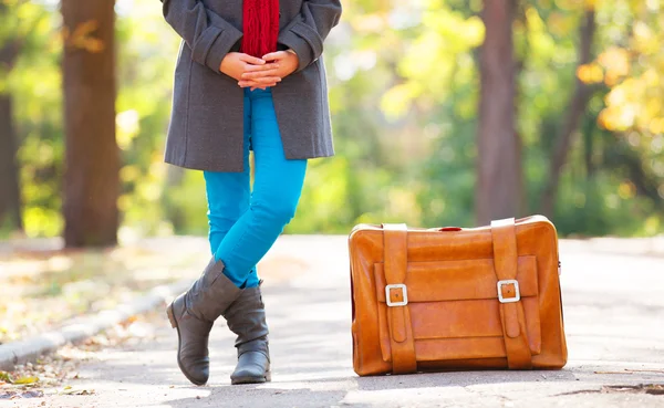 Frauenfüße neben Koffer bei Herbst-Outdoor. — Stockfoto