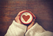 žena drží horký šálek kávy s tvaru srdce