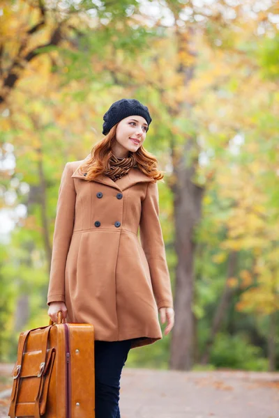 Pelirroja con maleta en otoño al aire libre — Foto de Stock