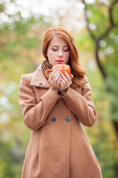 Redhead girl with cup in the park — Stock Photo, Image