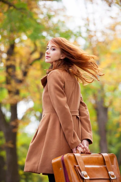 Pelirroja con maleta en otoño al aire libre — Foto de Stock