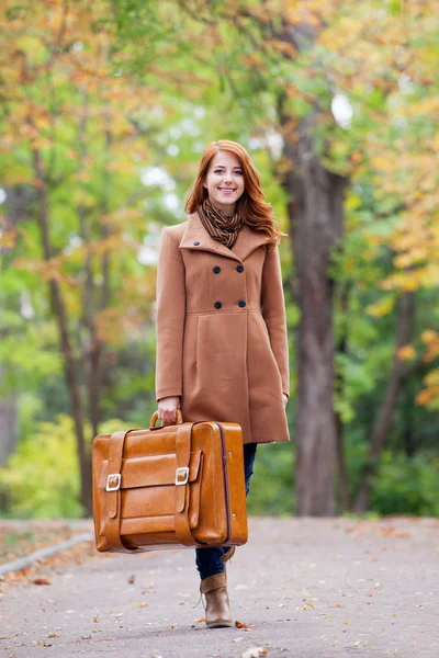 Rödhårig tjej med resväska på hösten utomhus — Stockfoto