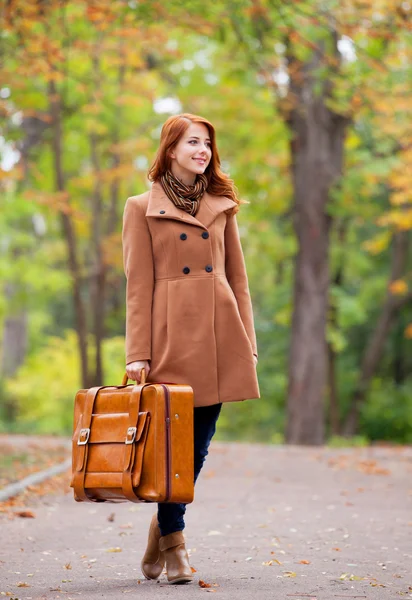 Pelirroja con maleta en otoño al aire libre — Foto de Stock