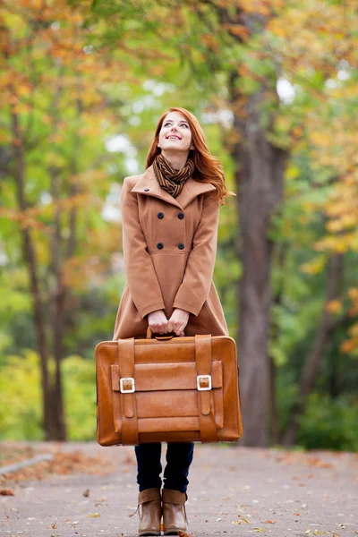 Pelirroja con maleta en otoño al aire libre — Foto de Stock