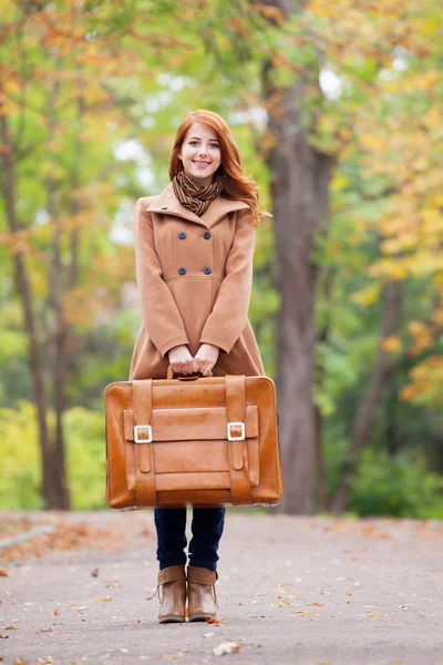 Roodharige meisje met koffer in herfst buiten — Stockfoto