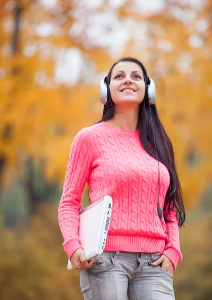 Portrait of a woman at outdoor with headphones and notebook. — Stock Photo, Image