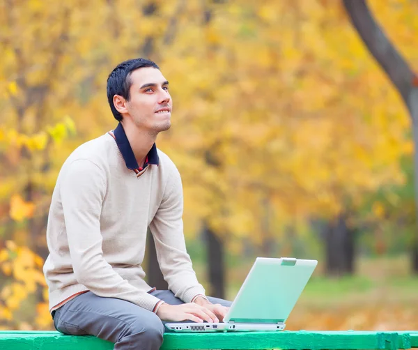 程序员与笔记本坐在秋天的公园 — 图库照片