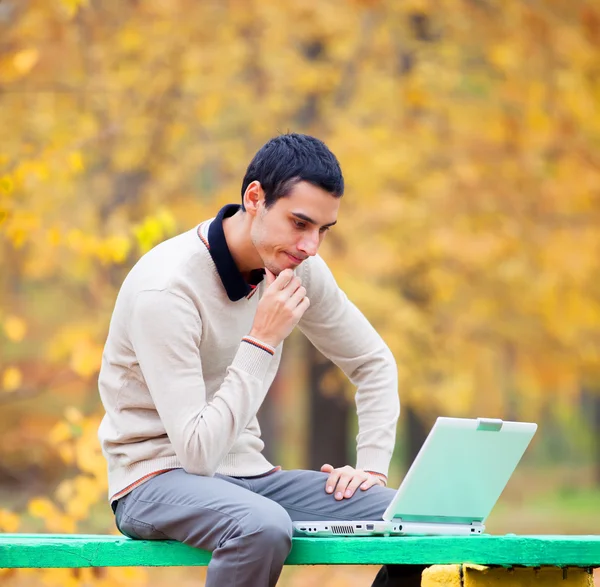 Programador com caderno sentado no parque de outono — Fotografia de Stock