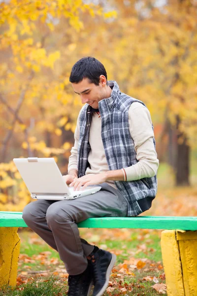 Programmatore con taccuino seduto nel parco autunnale — Foto Stock