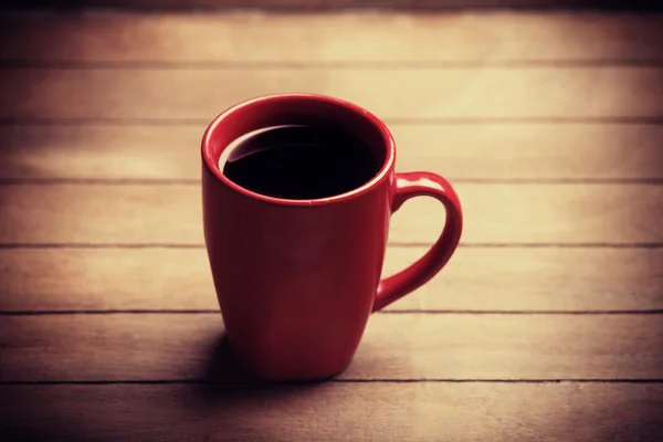 Red cup of coffee on wooden table — Stock Photo, Image