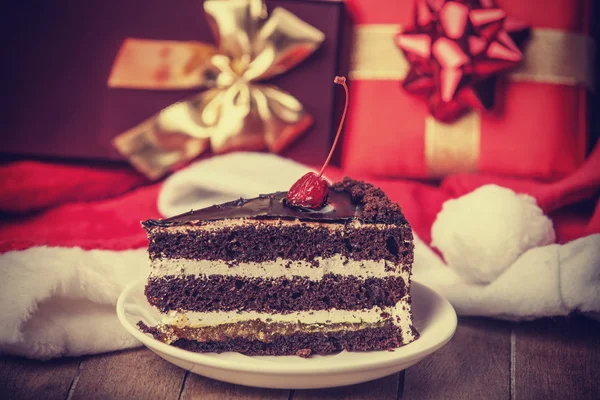 Bolo de chocolate e presentes de Natal no fundo — Fotografia de Stock