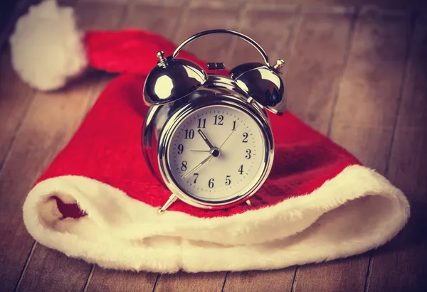 Retro alarm clock on table with christmas hat — Stock Photo, Image