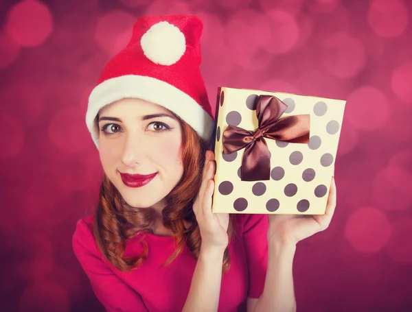 Fille rousse avec des cadeaux sur fond rouge — Photo