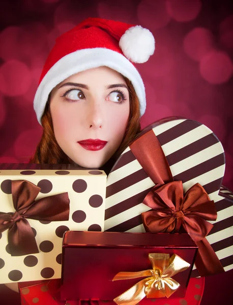 Pelirroja chica con regalos sobre fondo rojo — Foto de Stock