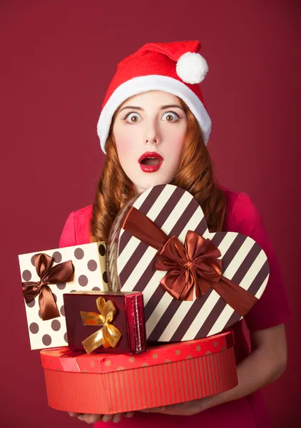 Pelirroja chica con regalos sobre fondo rojo —  Fotos de Stock