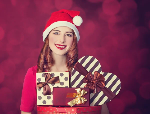 Рыжая девушка с подарками на красном фоне — стоковое фото