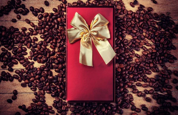 Rotes Geschenk auf Holztisch mit Kaffeekörner — Stockfoto