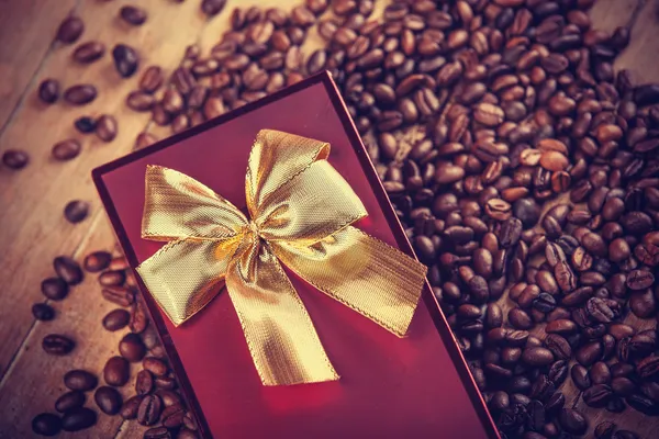 Presente vermelho na mesa de madeira com grão de café — Fotografia de Stock