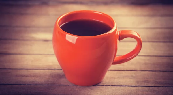 Czerwona filiżanka kawy na drewnianym stole — Zdjęcie stockowe