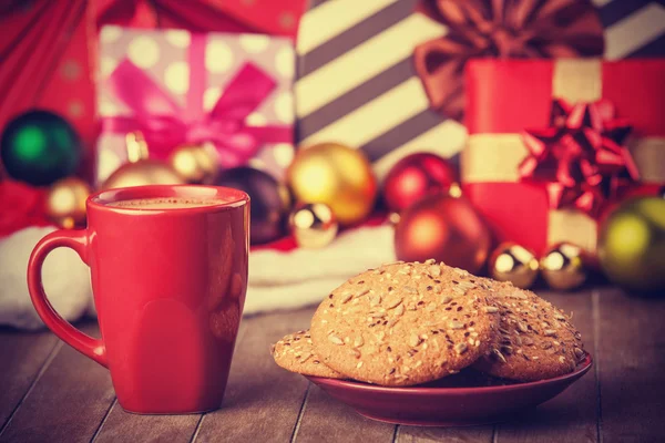 Cookies en kopje koffie met de giften van Kerstmis op achtergrond — Stockfoto