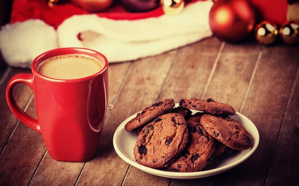 Biscoitos e xícara de café com presentes de Natal no fundo — Fotografia de Stock