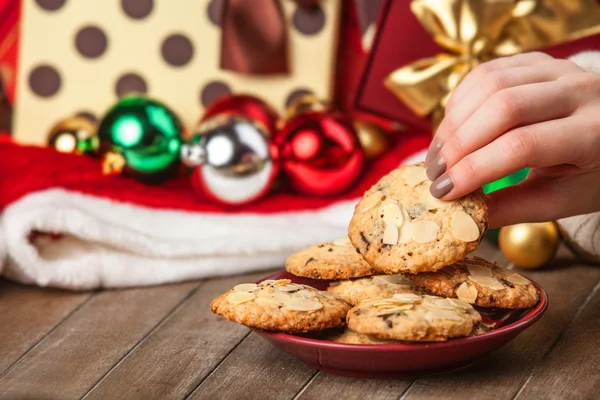 Mão feminina segurando biscoito no fundo do presente de Natal — Fotografia de Stock