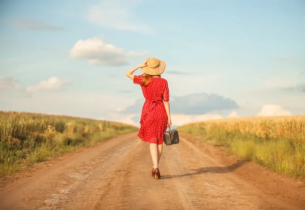 Rusovláska dívka s kufrem na venkovní. — Stock fotografie