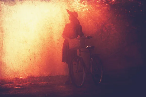 Chica en una bicicleta en el campo en el amanecer . — Foto de Stock