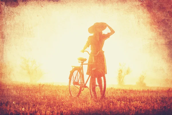 Meisje op een fiets op het platteland in zonsopgang tijd. — Stockfoto