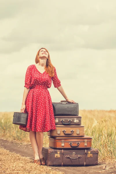Рыжая девушка с чемоданами на открытом воздухе — стоковое фото
