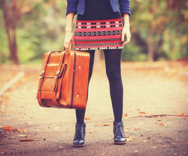girl with suitcase at autumn outdoor.