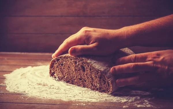 Las manos de Baker con un pan. Foto con alto contraste —  Fotos de Stock