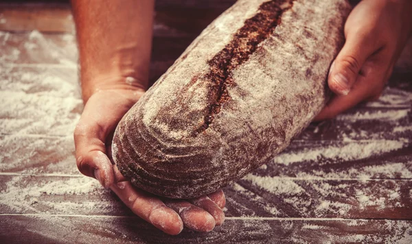 Baker's hands with a bread. Photo with high contrast — Stock Photo, Image