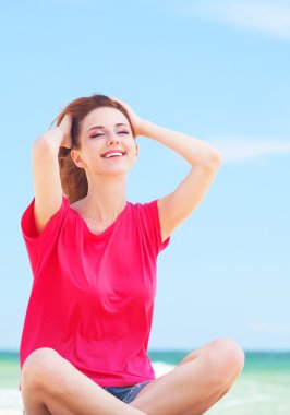 kum plaj üzerinde oturan genç kız.