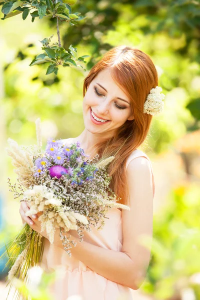 Roodharige meisje met bloemen bij buiten. — Stockfoto