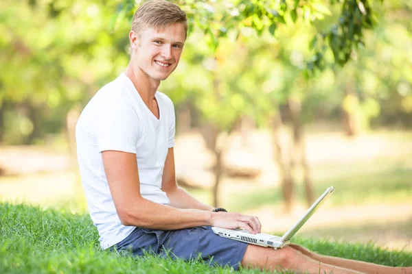 Teen pojke med laptop i parken. — Stockfoto