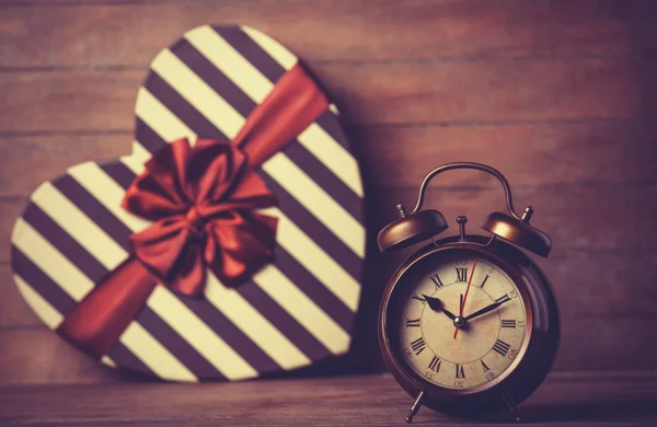 Retro clock and gift in heart shape on the background. — Stock Photo, Image