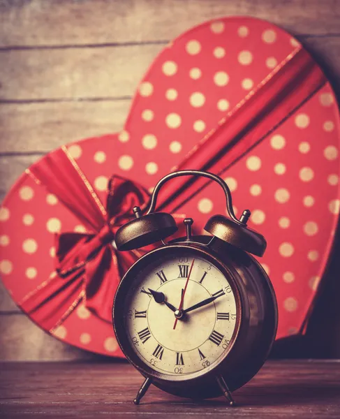Retro clock and gift in heart shape on the background. — Stock Photo, Image