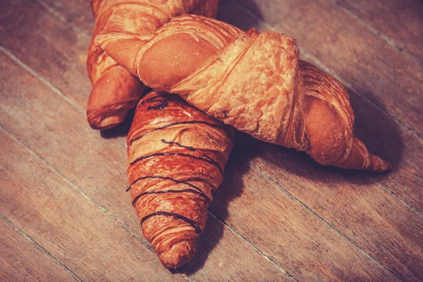 Verse croissants op de oude houten tafel — Stockfoto