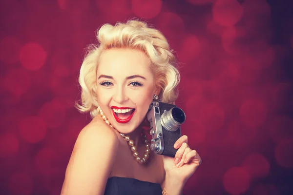 Beautiful blonde women with camera on red background. — Stock Photo, Image