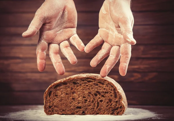 Baker's hands with a bread. — Stock Photo, Image