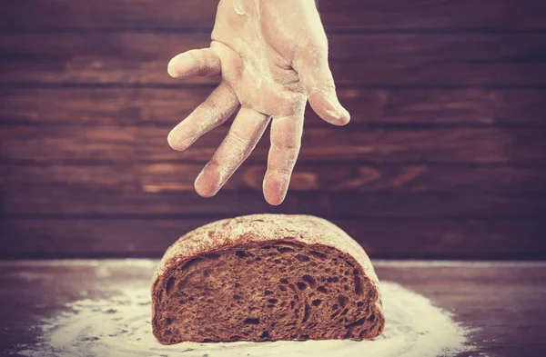 Baker's hands with a bread. — Stock Photo, Image