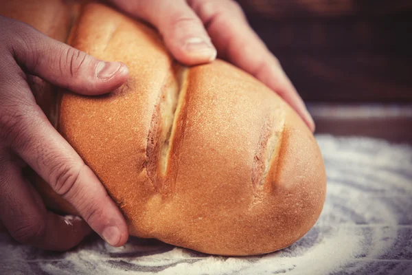 Baker's hands with a bread. — Stock Photo, Image