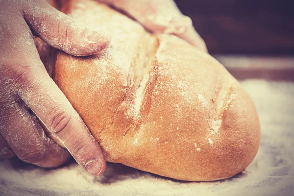 Baker's hands with a bread. — Stock Photo, Image